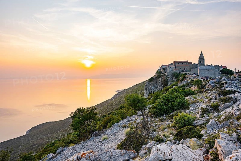 Small fishing village (Lubenice) built on the rocks high above the sea with a view of the sea on a sunny day at sunset on the island of Cres, Croatia