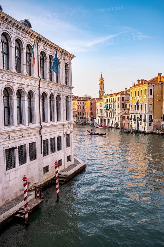 View of the Grand Canal with gondoliers at sunset, picturesque evening mood with palazzos on the canal and church tower of the Chiesa Parrocchiale dei Santi Apostoli, view from the Rialto Bridge, Venice, Veneto, Italy