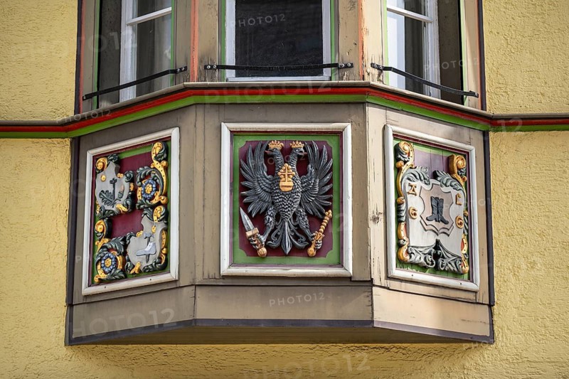 Detailed view of an ornately decorated bay window with heraldic motifs on a traditional town house in the historic centre of Rottweil. Centre field: A conspicuous double-headed eagle, a symbol often associated with the Holy Roman Empire or imperial history. Right field: A coat of arms with a boot, which could indicate a local guild coat of arms (possibly of shoemakers) or a family coat of arms, district of Rottweil, Baden-Württemberg, Germany
