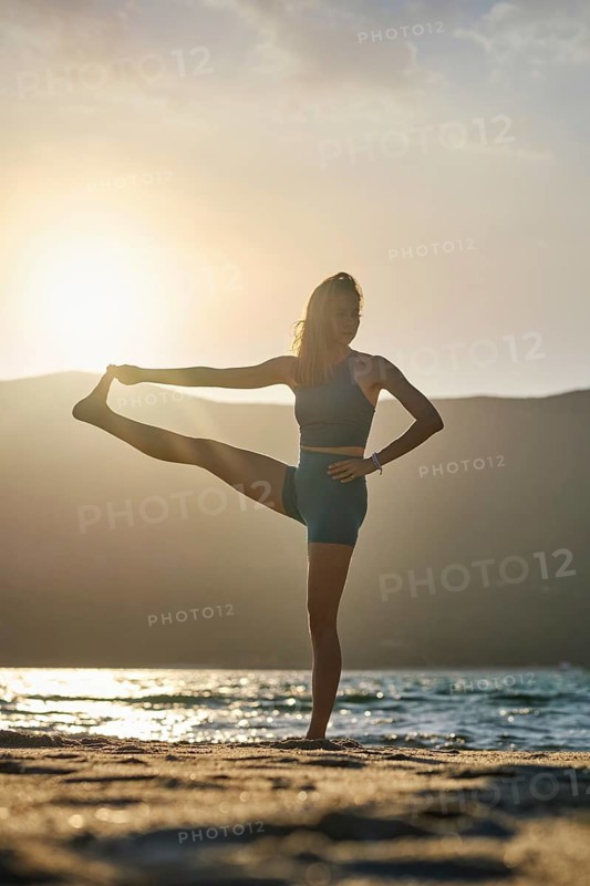 Yoga pose Utthita Hasta Padangusthasana Extended Hand-to-Big-Toe Pose at sunset on the beach