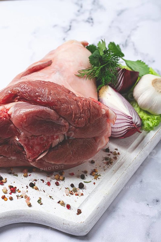 Raw pork knuckle, on a wooden chopping board, with spices, close-up, top view, no people