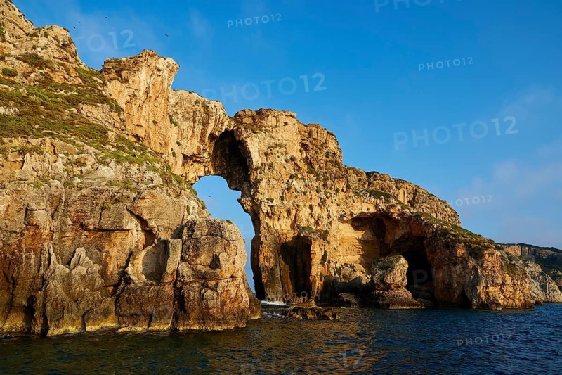 The arch of an impressive rock formation towering over the sea, morning light, Tsichli Babas islet, Navarino Bay, Pylos, Peloponnese, Greece