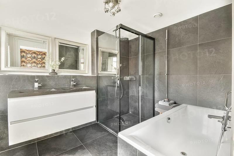 A stylish modern bathroom featuring sleek fixtures, a glass shower, elegant tiles, and a bathtub, designed for comfort and luxury