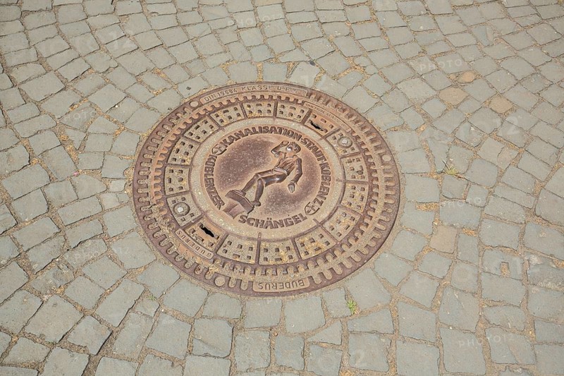Round manhole cover with angel figure, inscription, paving stones, floor, Koblenz, Rhineland-Palatinate, Germany