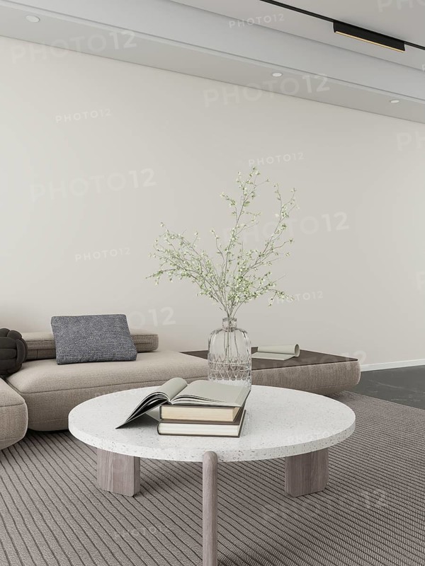 A serene living room featuring a textured sofa, sleek round table, open book, stacked books, and a vase of delicate flowers. Neutral tones and minimalist design create a tranquil ambiance