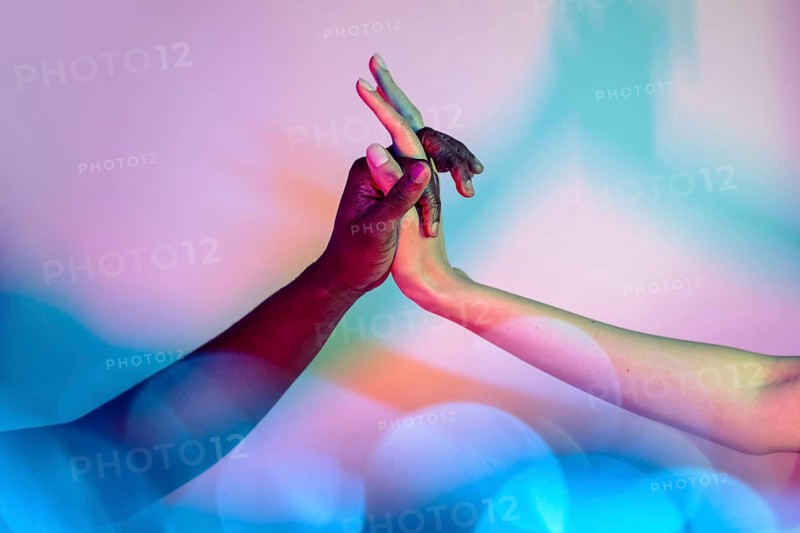 Multiethnic hands interlock against a colorful backdrop, symbolizing unity and diversity. This vibrant image highlights harmony and cultural connection through shared gestures