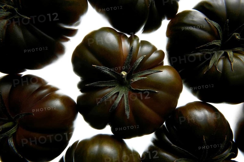 Top view of ripe heirloom black tomatoes on a light background, showcasing their rich, deep color and unique shape. Ideal for culinary, agriculture, or food themed projects