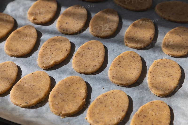 Easter cookies in egg shape prepared for baking on a baking tray with baking paper