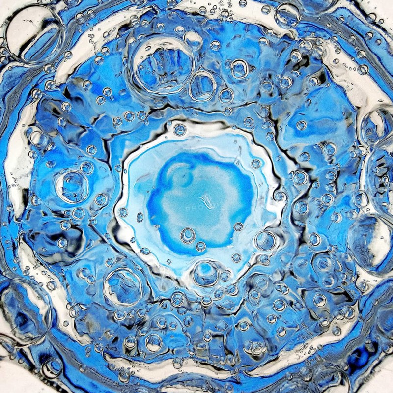 Rising carbon dioxide bubbles in a full water glass with a blue bottom seen from above, detail, Witten, North Rhine-Westphalia, Germany
