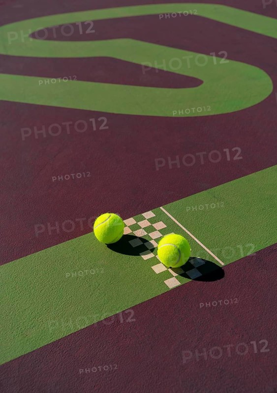 Vibrant close-up of three tennis balls on a uniquely designed court, featuring a contrast of green and purple hues with a checkerboard pattern