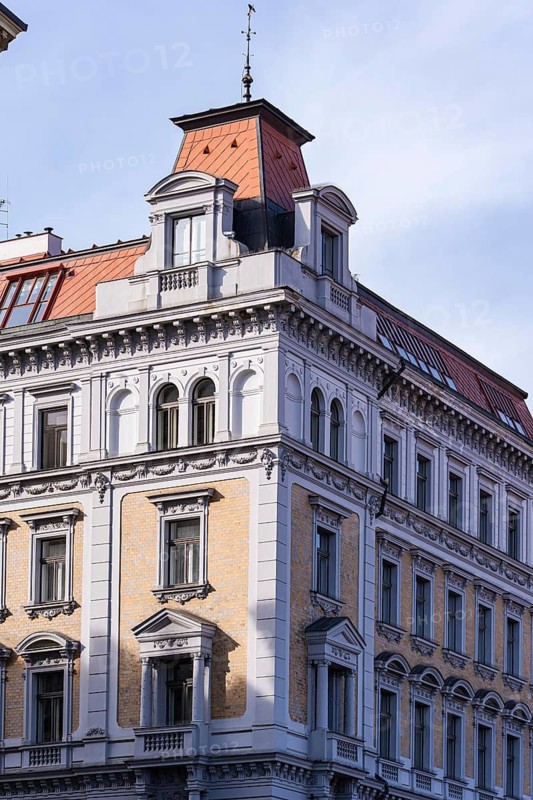 Elegant Prague building showcasing historical architecture with ornate details and red-tiled roofs, basking in sunlight. Classic European facade and intricate design elements