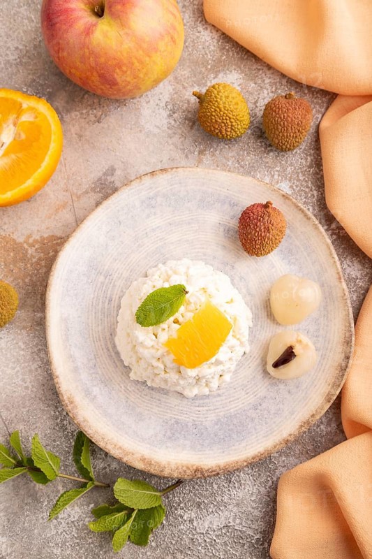 White ?ottage cheese, Curd, with orange and lychee on brown concrete background and orange textile, top view, flat lay, close up