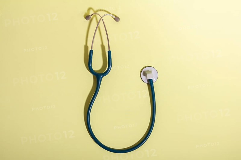 A stethoscope lies on a smooth yellow background, representing the medical profession and healthcare. The image highlights the importance of sanitary medical equipment in patient care