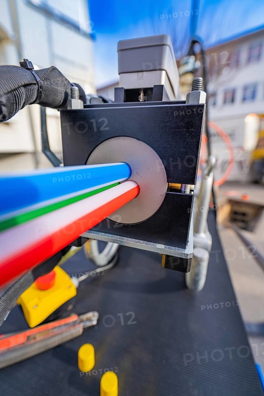 Technical device with three coloured cables from a guide, Wend Glasfasermontage during the jetting of conduits for fibre optic cables, Meßkirch, district of Sigmaringen, Germany