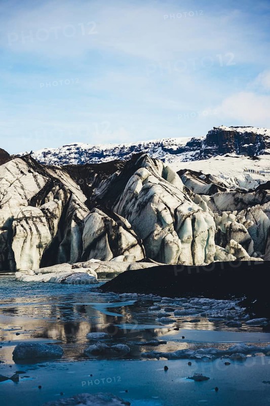 A stunning view of an Icelandic glacier with huge furrowed ice formations reflected in the water