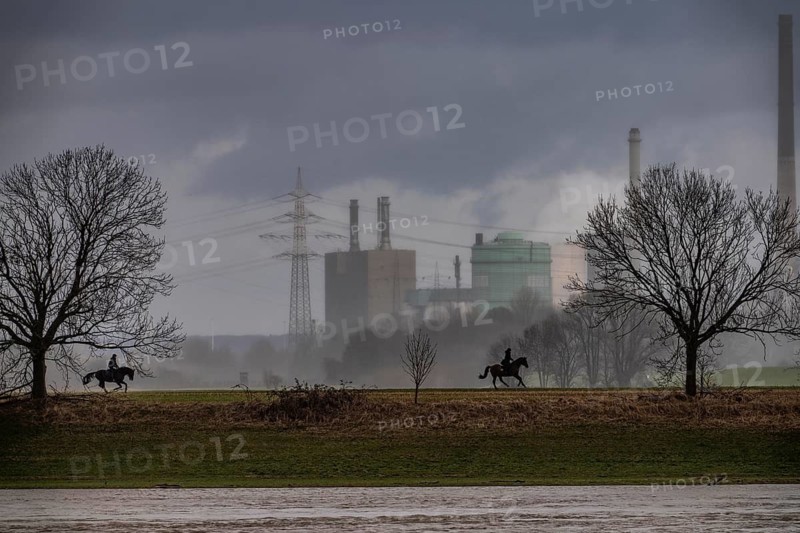 Riders on the banks of the Rhine opposite Krefeld-Uerdingen, in winter, the Krupp-Mannesmann metallurgical plant, HKM in Duisburg-Hüttenheim, coking plant, gas power plant, cooling towers, Rheinauen in Duisburg-Mündelheim, North Rhine-Westphalia, Germany