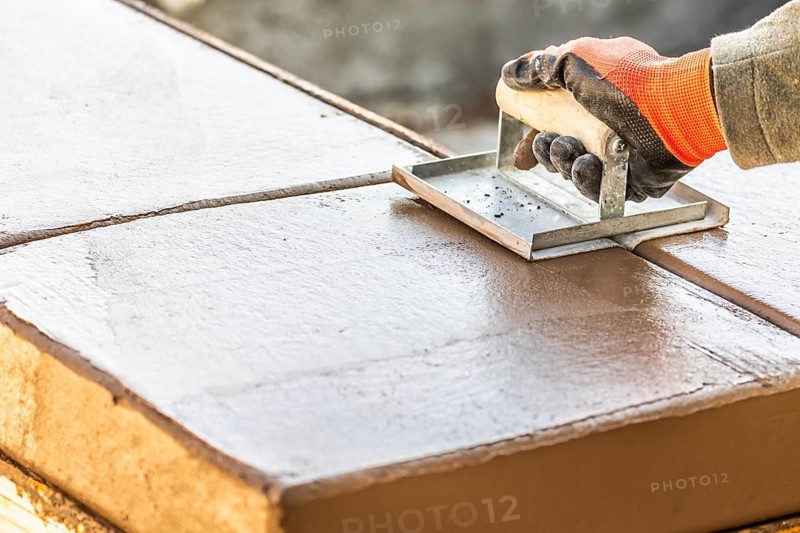Construction Worker Using Hand Groover On Wet Cement Forming Coping Around New Pool