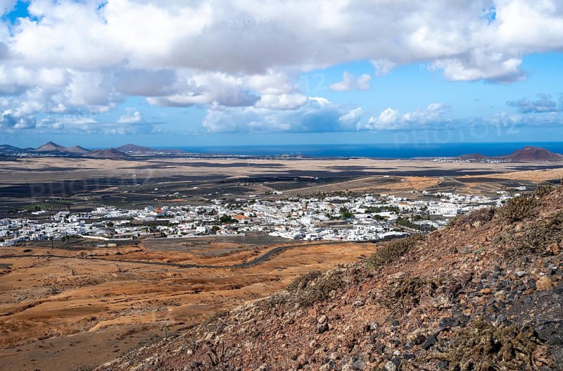 View of town, white houses of Teguise with church tower in dry volcanic landscape, view from Guanapay volcanic crater, Lanzarote, Canary Islands, Spain