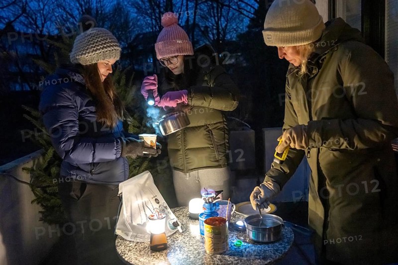 Symbolic picture blackout, extensive, prolonged power failure, in private surroundings, without electricity, heating, water, cooking, heating food and water with a gas-powered camping stove, on the balcony