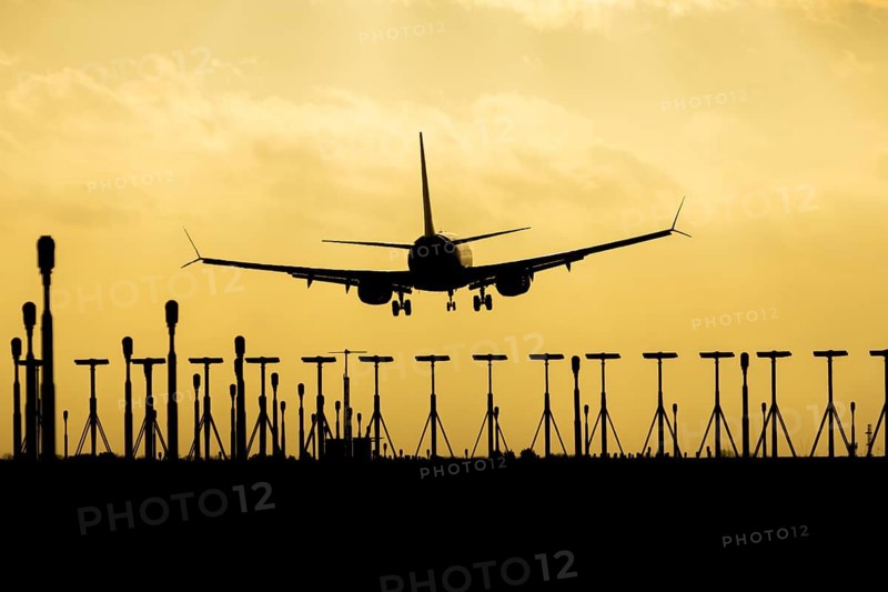 Boeing 737 commercial passenger airliner jet aircraft of Ryanair airways in flight on approach to land over runway lights at sunset at London Stansted airport, Essex, England, United Kingdom