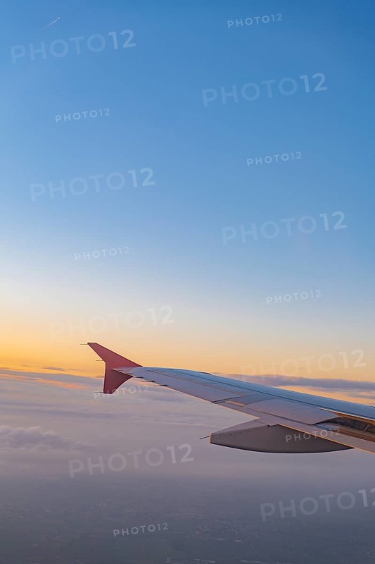 A scenic view from an airplane window highlighting the aircraft's wing against a breathtaking sunset sky. This image captures the essence of air travel and wanderlust