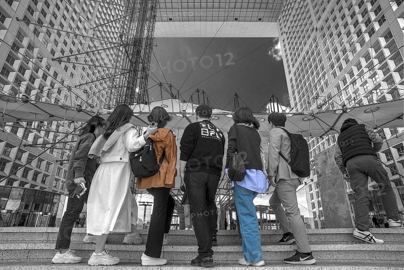 Tourists take a souvenir photo in the Grand Arche, La Défence, the New High City Quarter, black and white, Paris, France