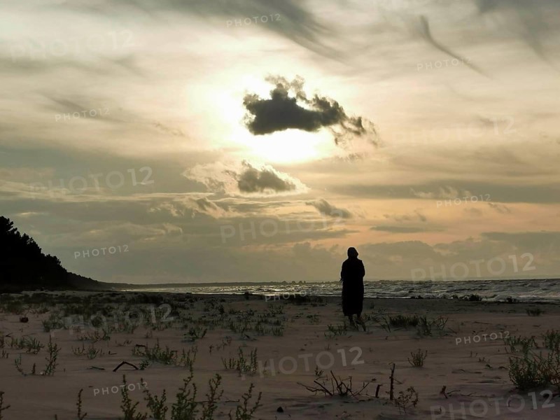 A silhouette of a person on the beach at sunset with dramatic sky, fresh spit, Baltic Sea, Poland