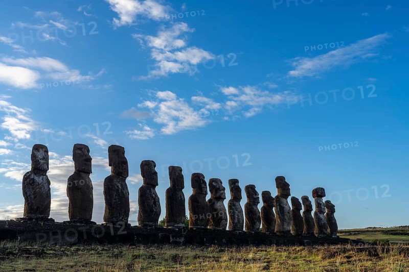 Row of fifteen Moai statues on the Ahu Tongariki stone platform against blue sky with clouds, Rapa Nui National Park, Easter Island, Chile