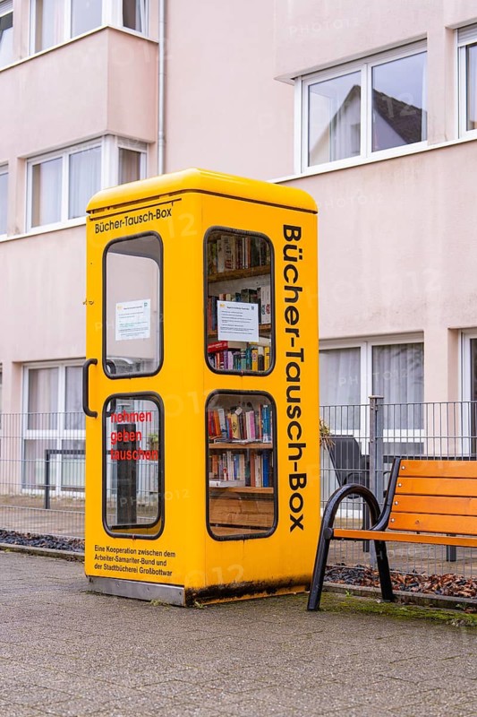 Yellow book exchange box in front of a residential building. Inviting for passers-by, Großbottwar, Ludwigsburg district, Baden-Württemberg, Germany