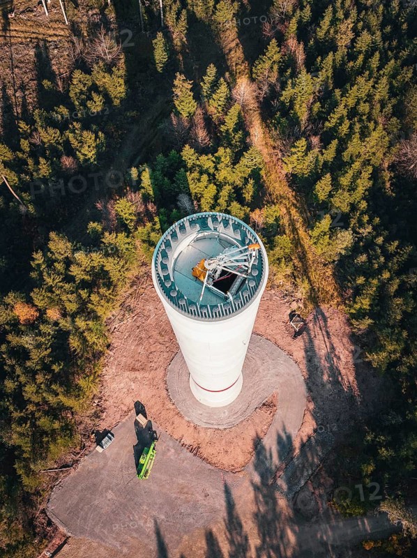 A bird's eye view of a wind turbine under construction surrounded by dense forest, Windrad Bau, Calmbach, Black Forest, Germany