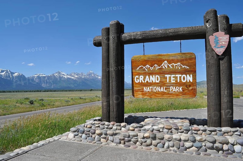 Wooden sign of Grand Teton National Park against mountain backdrop on a sunny day, Grand Teton National Park, Wyoming, USA
