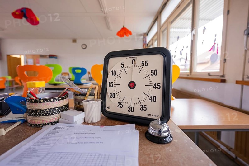 In a light-flooded room, there is a timer and a table bell on a desk, homework supervision, Schlehengäu Grund Schule Gechingen, Calw district, Germany