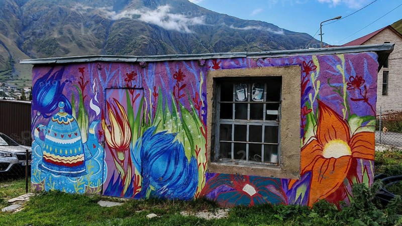 Artfully painted house against a mountain backdrop, vivid colors, Caucasus, Georgia