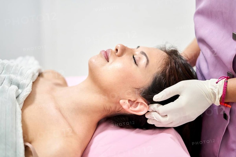 A client enjoys a soothing beauty treatment at an aesthetic medicine clinic, where a professional carefully performs a massage to enhance relaxation and wellbeing