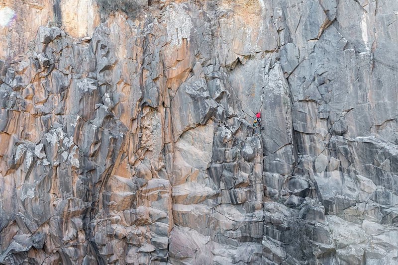 Two climbers tackles a challenging rock face using traditional climbing techniques. The scene captures the raw beauty of nature and the adventurous spirit required for the ascent