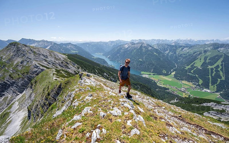 Mountaineer on the summit ridge of the Unnütz, behind Achensee and summit of the Seekarspitze Unnütz crossing, Brandenberg Alps, Tyrol, Austria