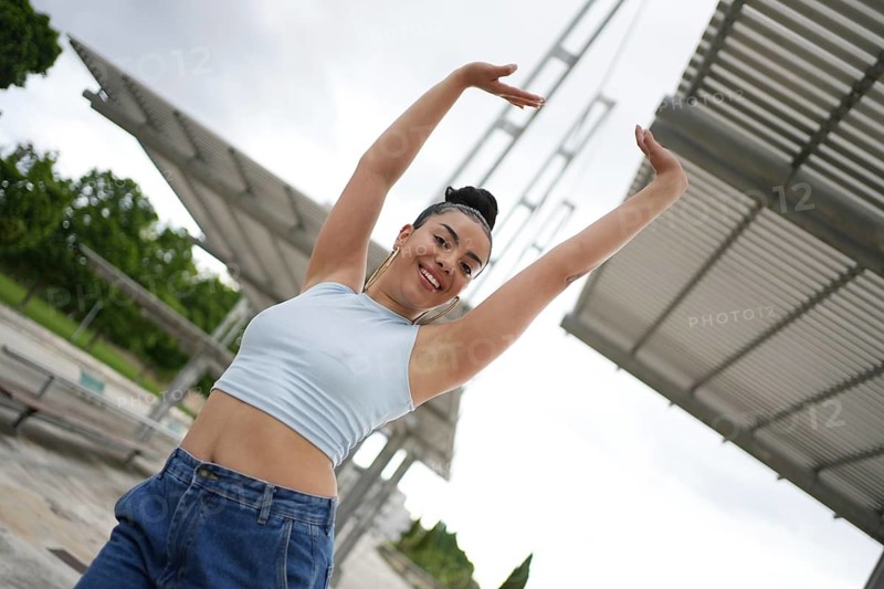 A woman is posing for a picture in front of a building. She is wearing a blue shirt and blue jeans