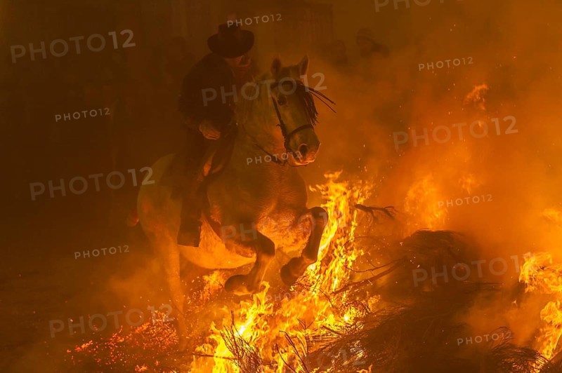 Europe. Spain. Avila. During the feast of San Antonio in the small mountain top hamlet of San Bartolome de Pinares a man jumps with his horse through one of the bonfires across one of the streets. This represents purification of the animals through fire