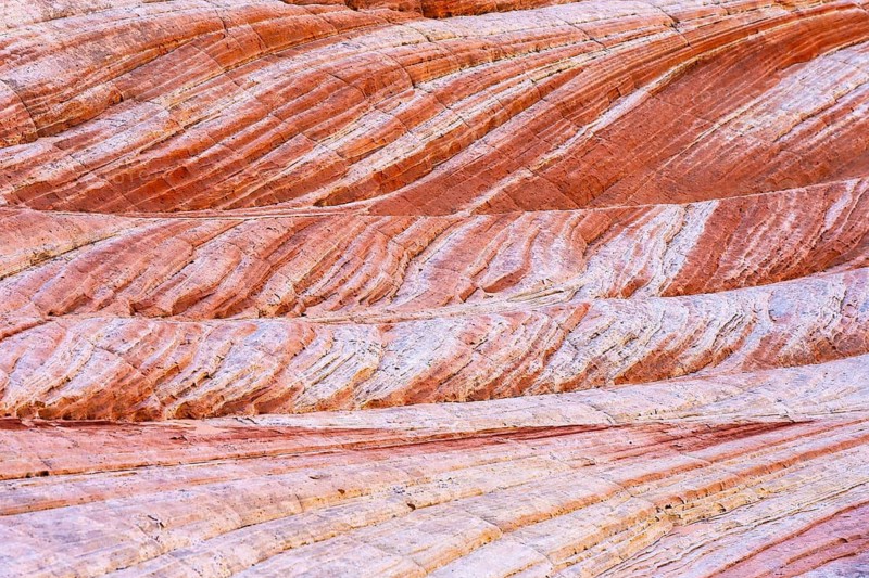 A close-up of naturally textured red rock sediment layers, showcasing vibrant striations and weathered lines