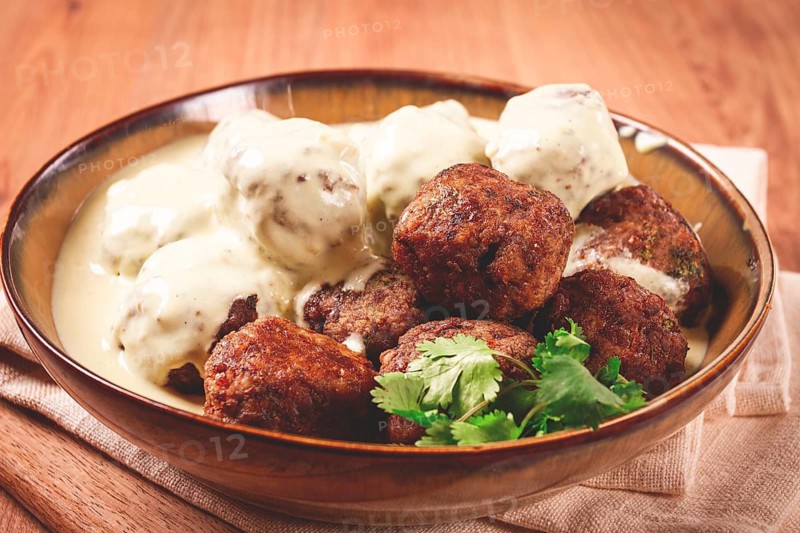 Swedish meatballs in cream sauce, plate on a wooden table, homemade, no people