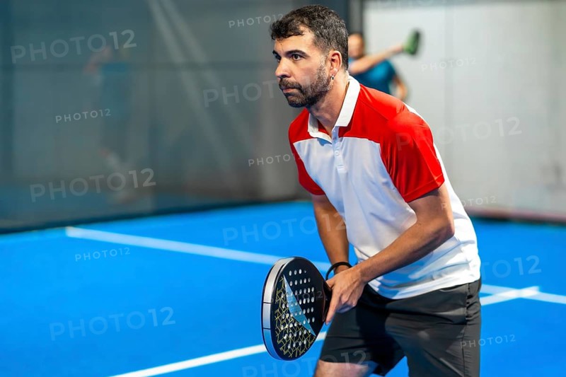 Side view portrait of a mature sportive man playing paddle tennis in an indoor court