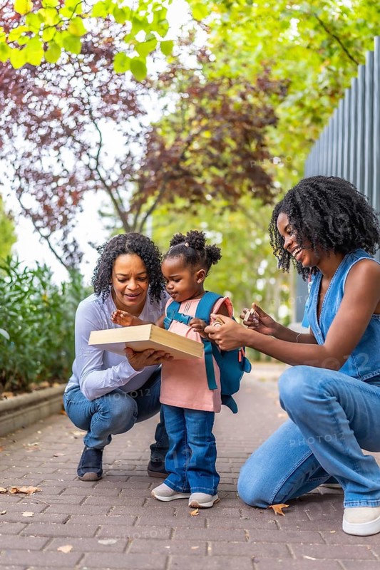 Vertical portrait of african three generation females in the city enjoying picking up a girl from school