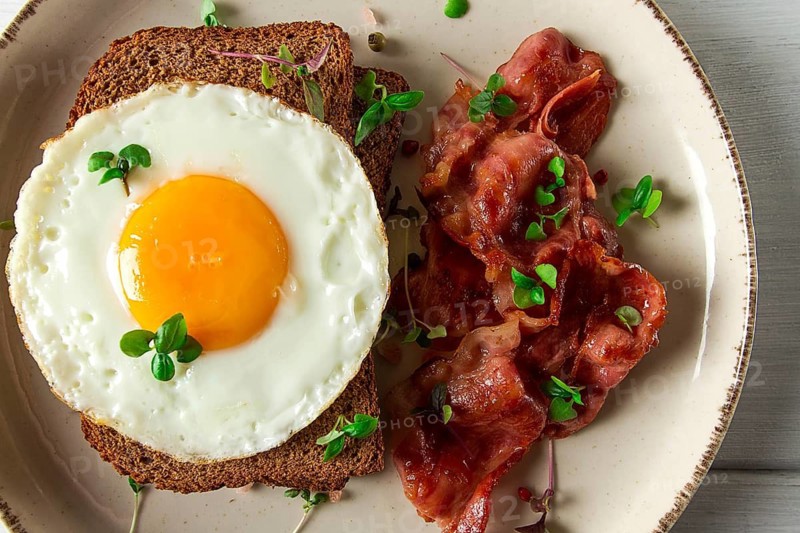 Breakfast, fried egg with bacon, micro-green, on a light background, no people, selective focus