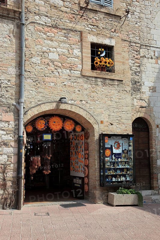 Window with a bunch of plastic flowers, sunflowers, in the historic centre of Assisi, Umbria, Italy