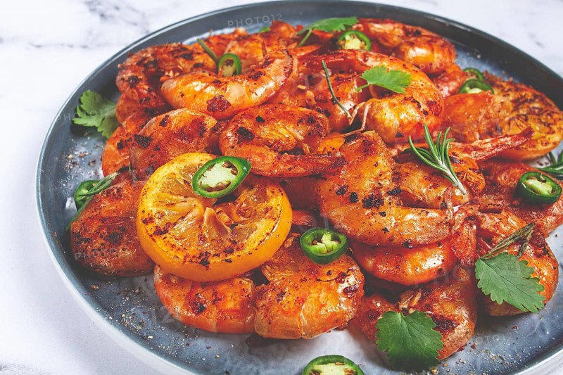 Grilled shrimp, unpeeled, headless, with spices, on a marble table, homemade, no people