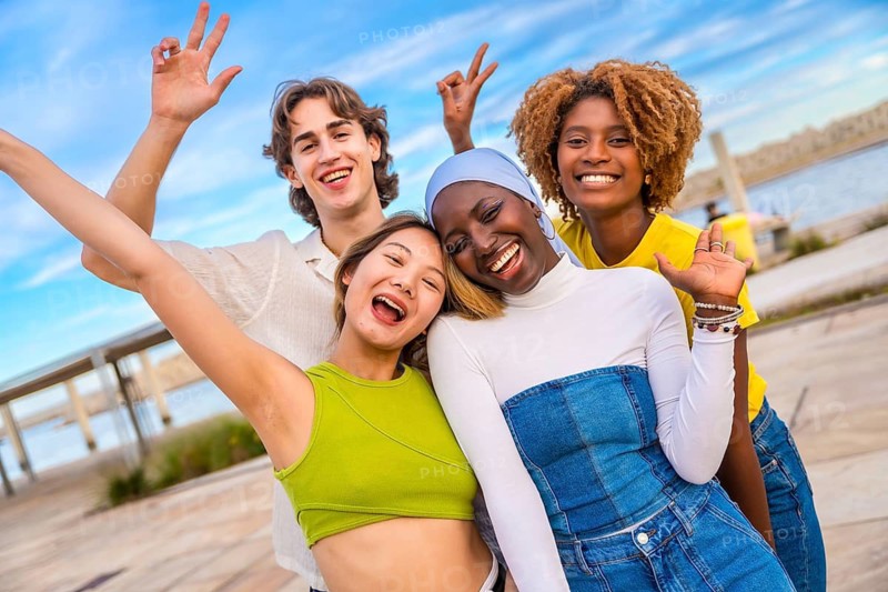 Multi-ethnic friends gesturing peace while smiling in an urban space