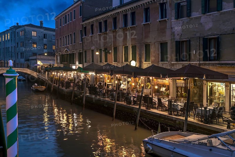 In the evening, illuminated restaurant on the canal, Venice, Veneto. italy