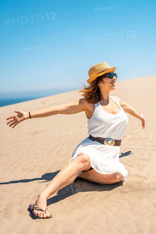 Woman raising hands against the wind in an idyllic and free summer on the beach in Cabo de Gata, Spain