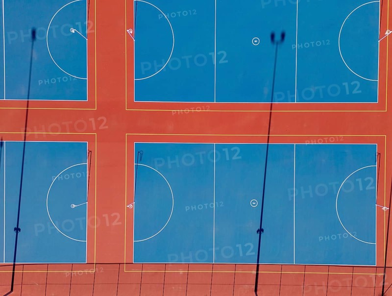 Top view captured by drone showcasing multiple vibrant netball courts in Canberra. The image illustrates the clear markings and layout of the courts with striking color contrasts