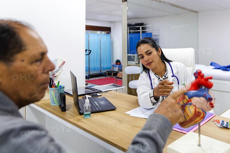 Young female doctor provides professional care to an elderly male patient in a Latin American hospital. She explains medical information attentively, fostering a supportive environment
